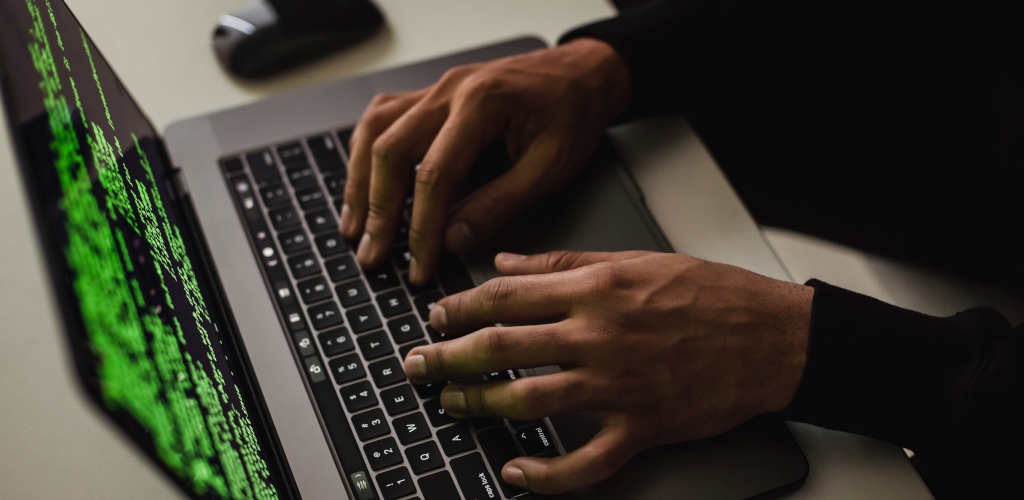 a set of hands typing green letters on a black screen