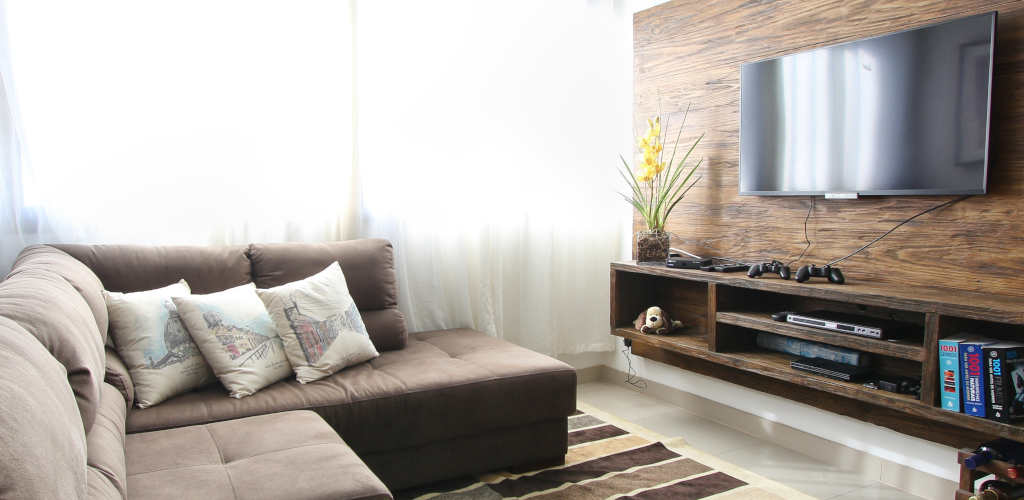 A wall mounted TV in front of a comfy-looking couch