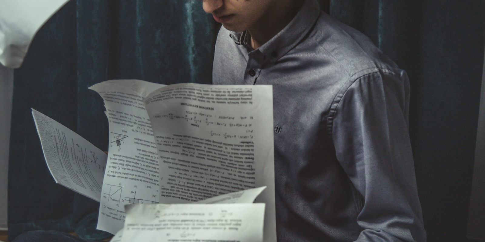 A student leafing through loose printed paper