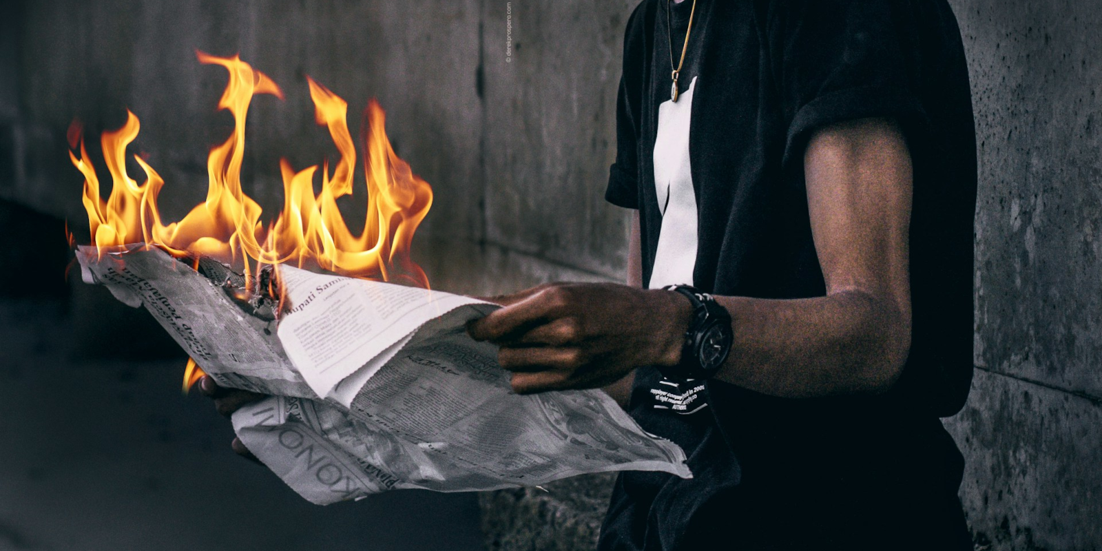 man reading a newspaper that is on fire