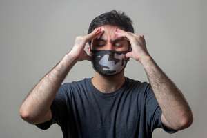 A man clutching his head and wearing a mask - Photo by https://unsplash.com/photos/man-in-black-crew-neck-t-shirt-wearing-black-and-white-mask-Dd6St65dfYw