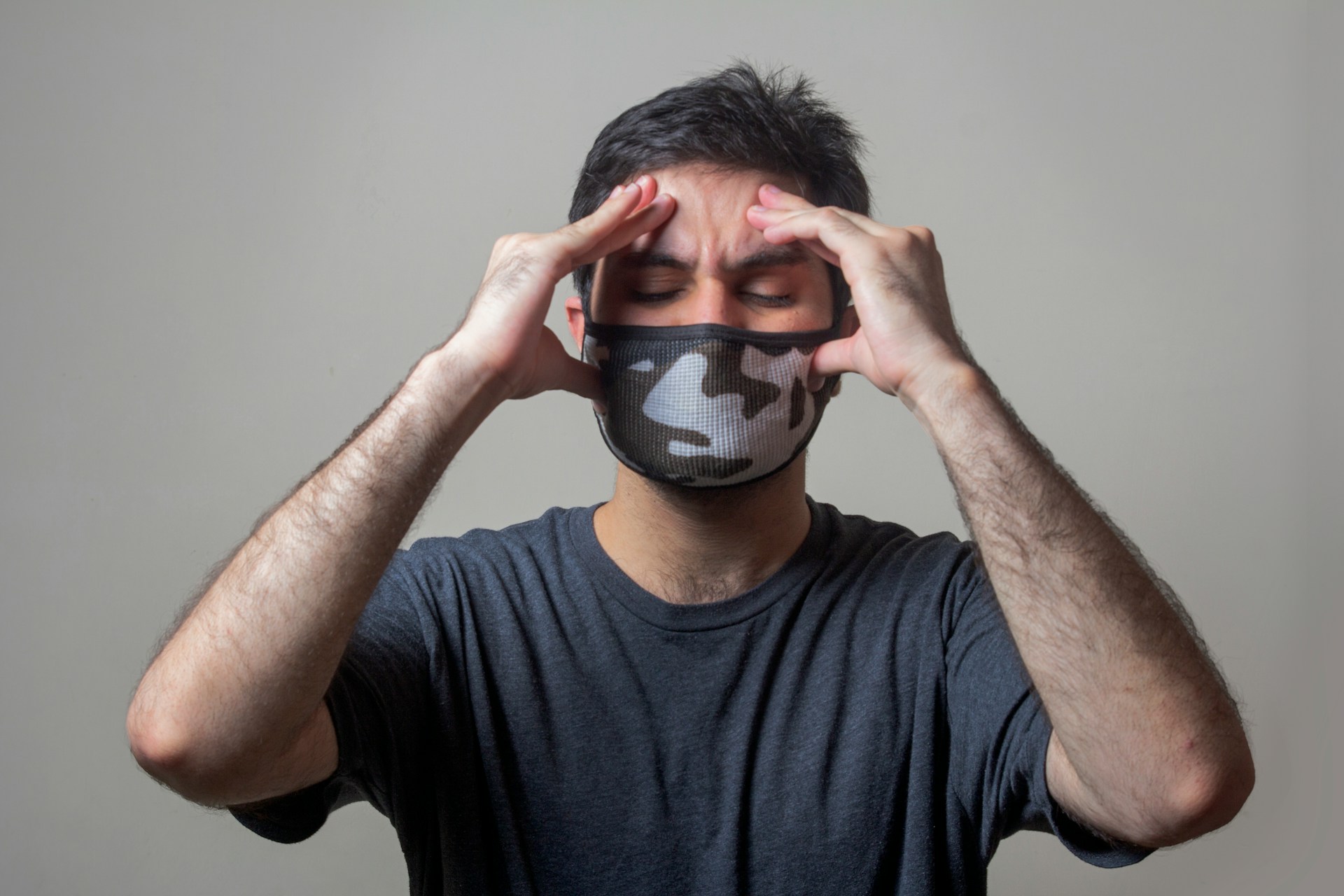 A man clutching his head and wearing a mask - Photo by https://unsplash.com/photos/man-in-black-crew-neck-t-shirt-wearing-black-and-white-mask-Dd6St65dfYw