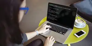 A woman with glasses using the terminal on a laptop