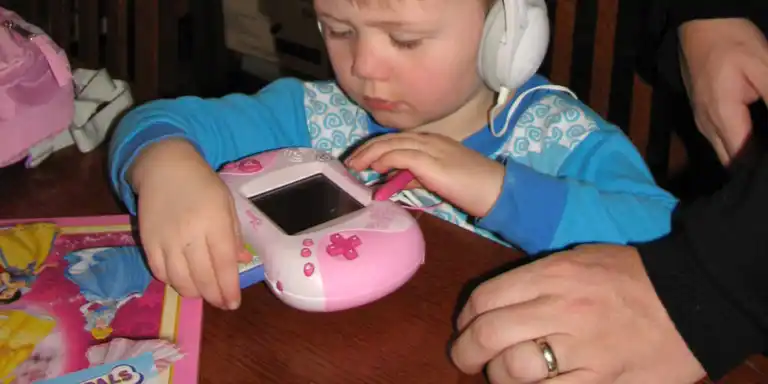 Boy inserting a cartridge into a pink Leapster