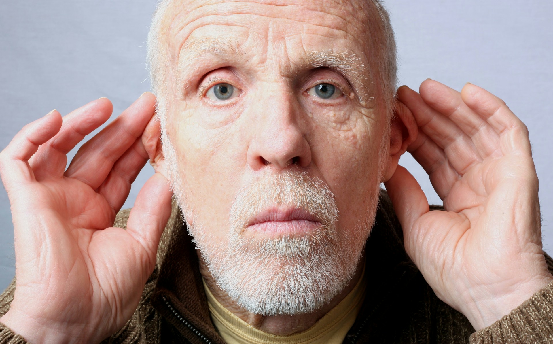 A man holding both hands up to his ears
