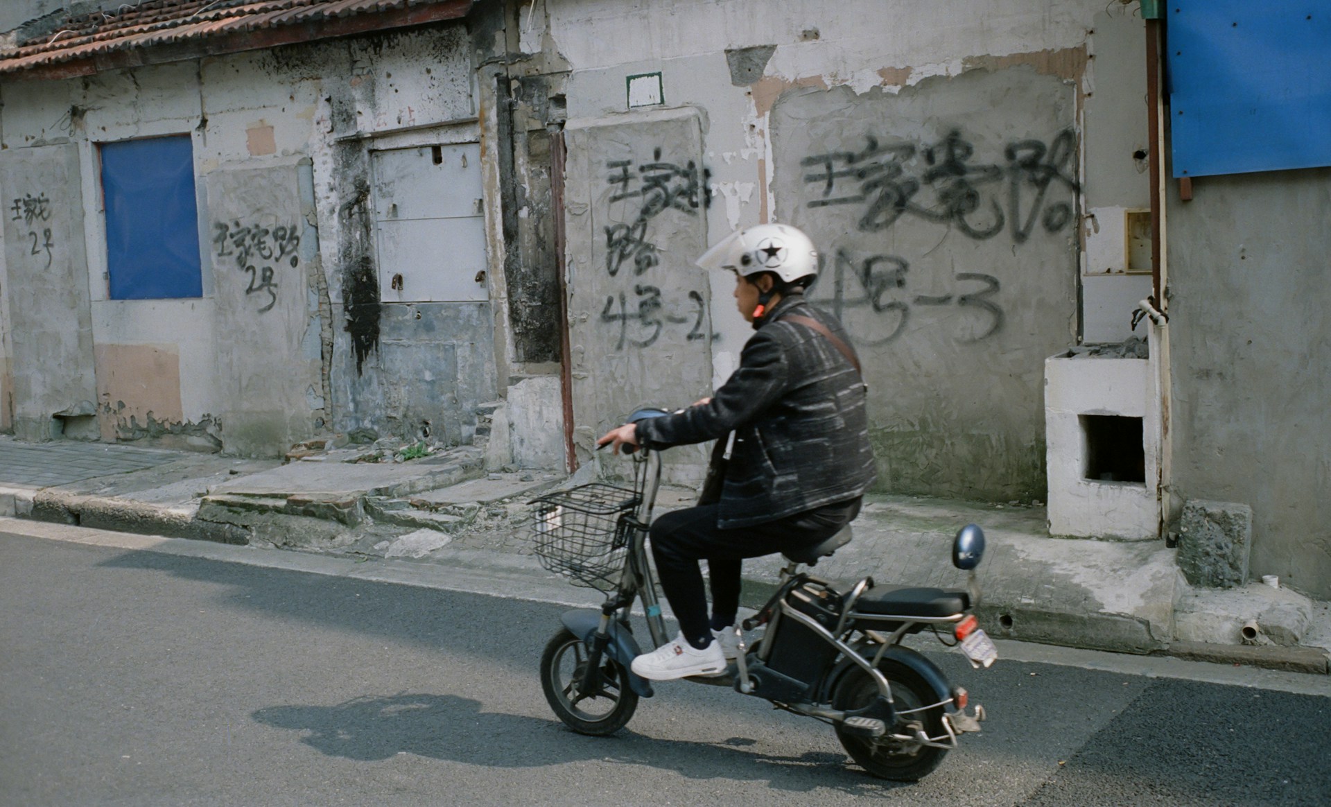 Scooter rider passing a grafittied wall