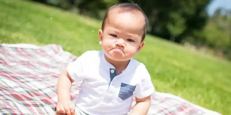 A sad baby on a picnic blanket