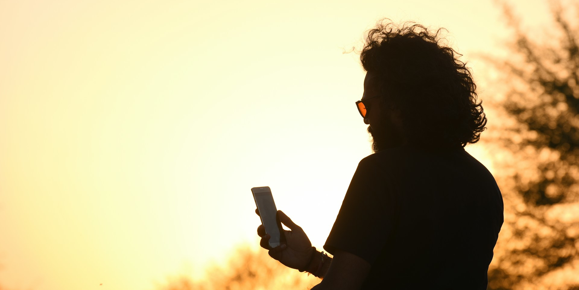 silhouette of a bearded man looking at his phone