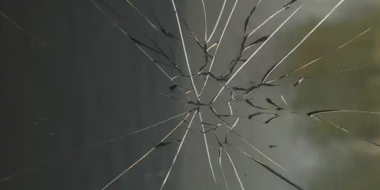 A pane of glass smashed as if hit by a single stone