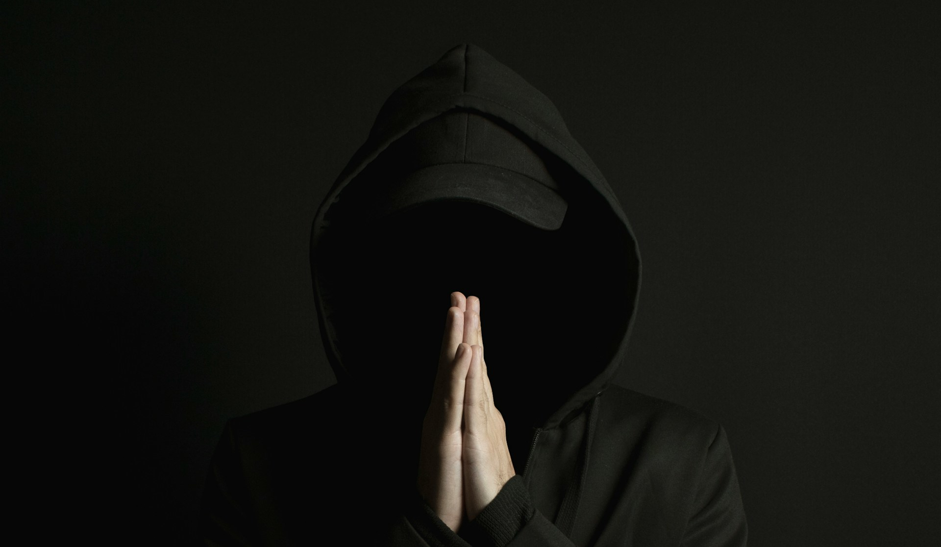 Sinister dude in a hoody. His face can't be seen, and his hands are in prayer position