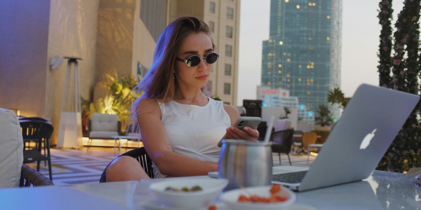 A woman in sunglasses using a laptop outdoors