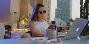 A woman in sunglasses using a laptop outdoors
