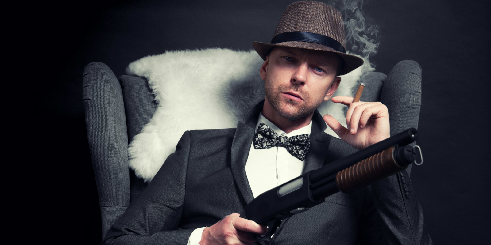 A man with a shotgun sitting in a chair smoking a cigar
