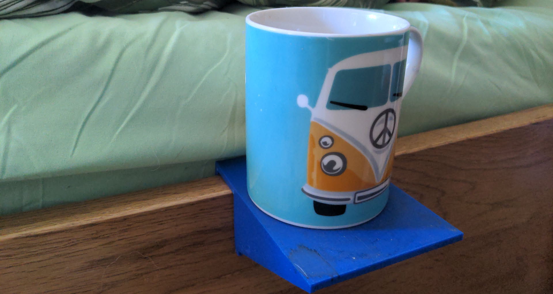 A volksgen mug on a stained blue sliding table mounted on a bed rail