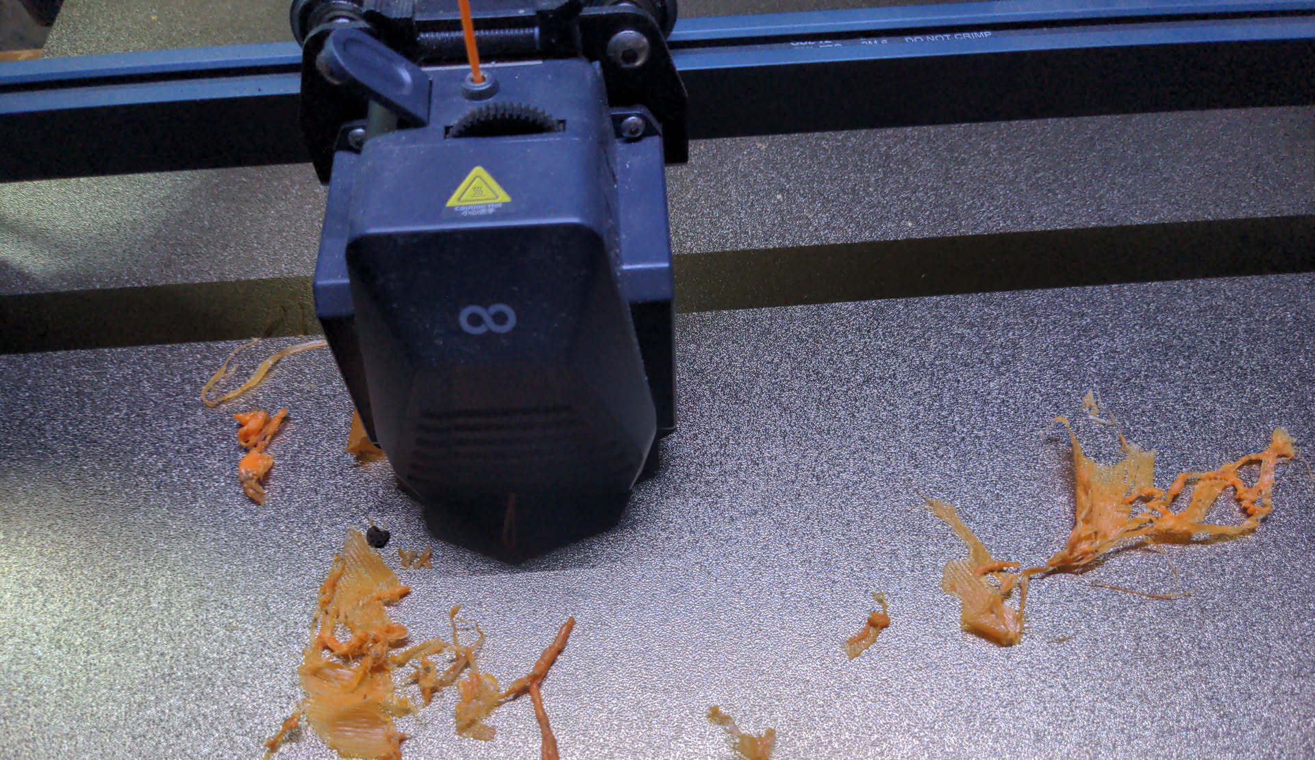 Failed print resulting in meted orange filament over the printbed