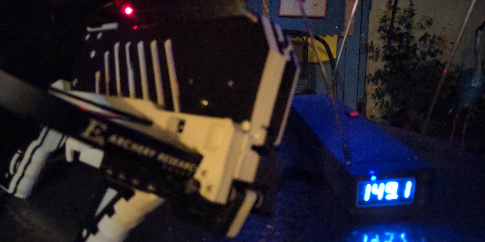 A black and white repeating crossbow next to a chronograph at night